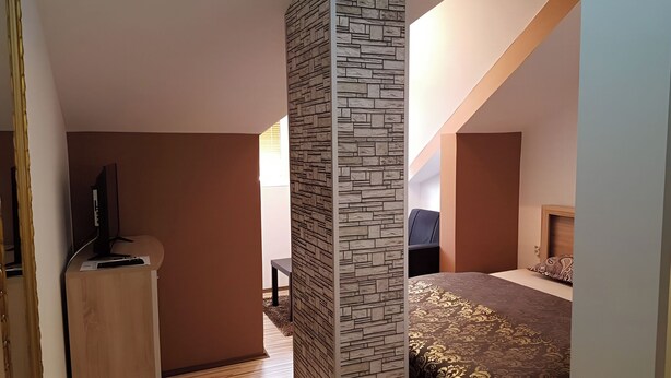 Un dormitorio con cama, televisor y una pared de detalles de piedra.