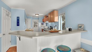Una cocina con una isla blanca, paredes azules y armarios de madera.