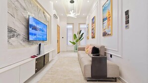 Ein modernes Wohnzimmer mit Flachbildfernseher, einer Couch und Kunstwerken an den Wänden.