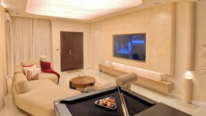 Una sala de estar moderna con mesa de billar, asientos cómodos y un televisor de pantalla plana montado en la pared.