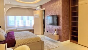 Un dormitorio moderno con cama, televisión, armario y ventana.