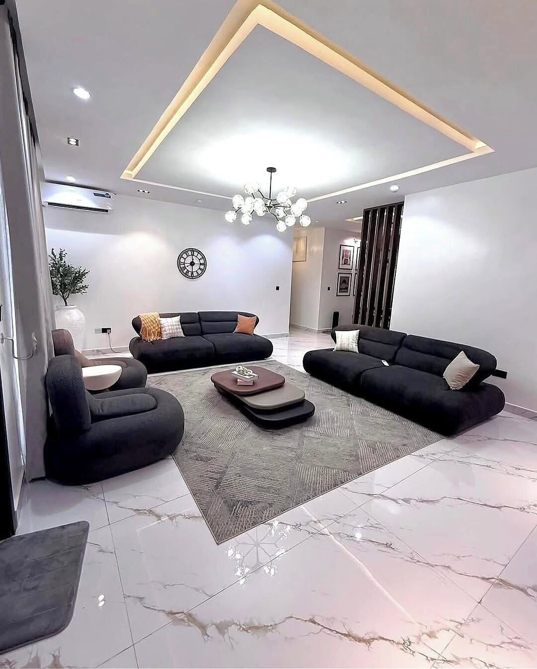 A modern living room with a sectional sofa, a coffee table, and a chandelier.