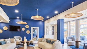 A modern lounge area with sofas, round tables, and hanging wicker lamps. - Bleu Canopée by Interhome (Mimizan)