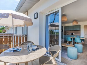 Eine Terrasse mit rundem Tisch, Stühlen und Sonnenschirm.