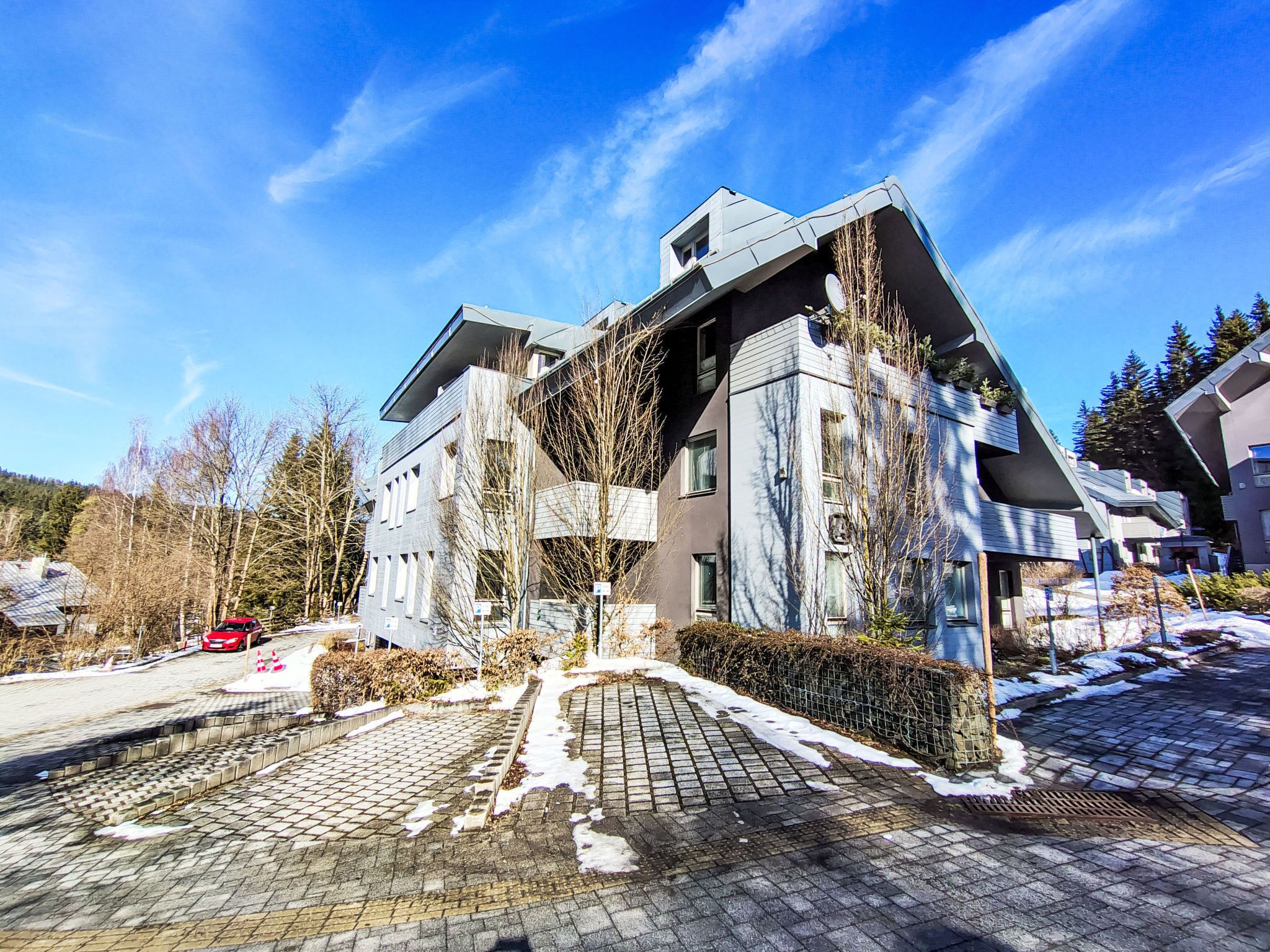 A modern building with a unique architectural design, featuring multiple balconies and a sloped roof.