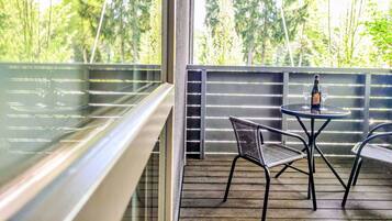 A balcony with a table and chairs, overlooking a forested area.