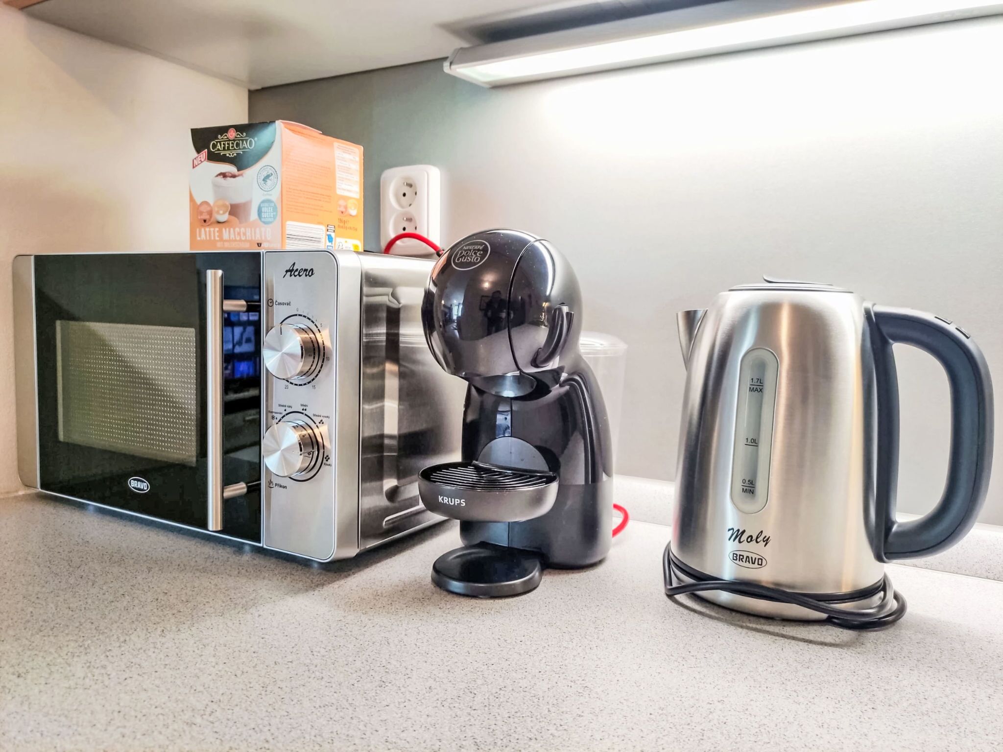 A kitchenette with a microwave, coffee maker, and kettle.