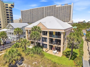 A multi-story building with balconies, surrounded by palm trees and a clear sky. - Beachfront escape - steps from the Gulf (Panama City Beach)