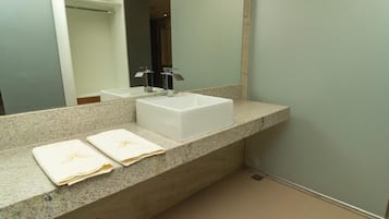 A bathroom with a white sink, a large mirror, and two towels on the counter.