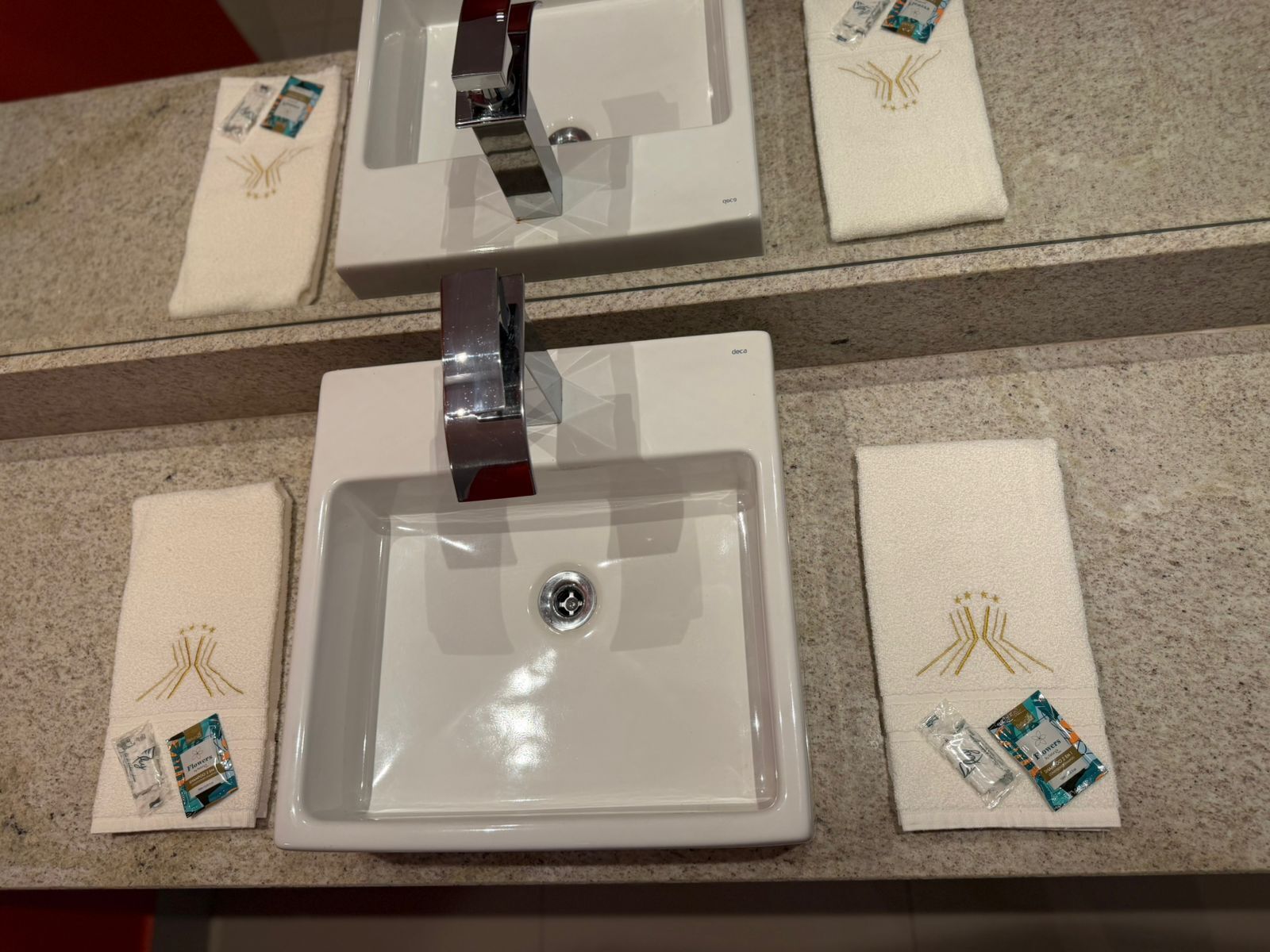 A bathroom with three sinks, each with a towel and toiletries.