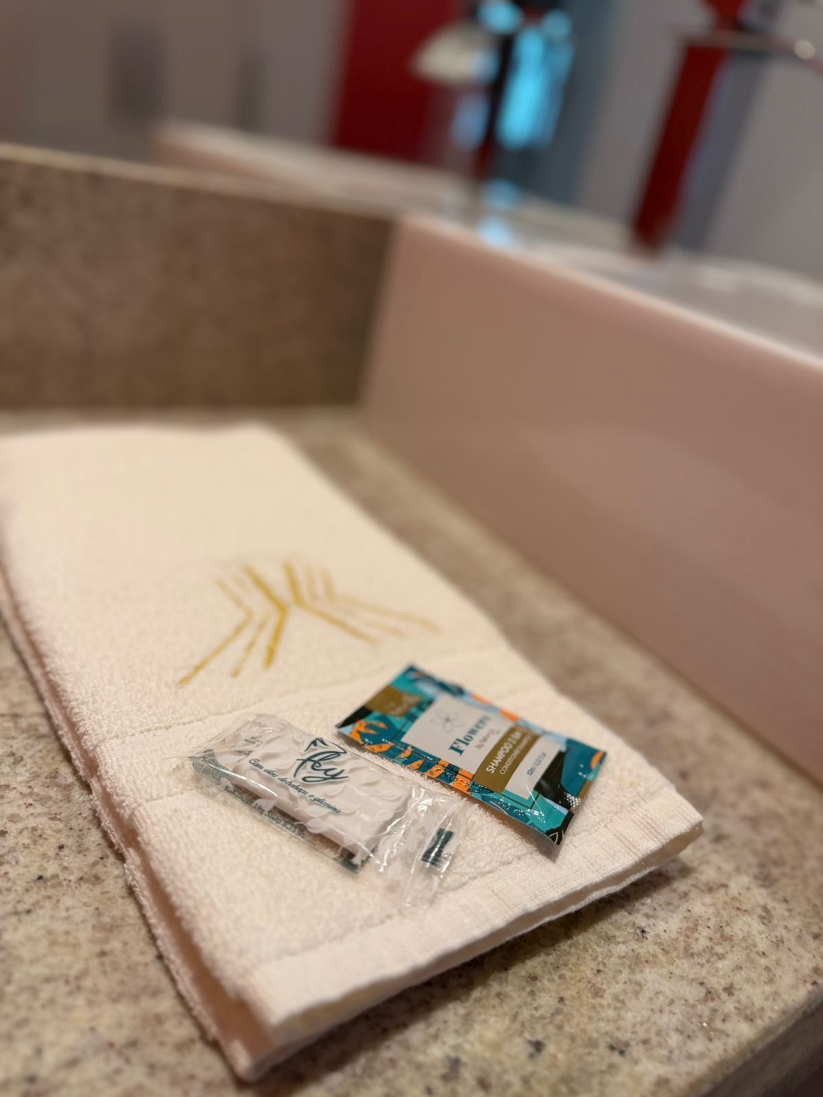 Une salle de bain avec une serviette beige, une brosse à dents et un flacon de shampoing posés sur un comptoir.