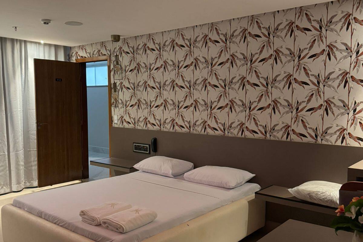 A modern hotel room with a large bed, a desk, and a bathroom visible through an open door.