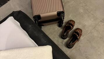 Una habitación con una maleta grande, un par de zapatos y una almohada con bordado de estrella.
