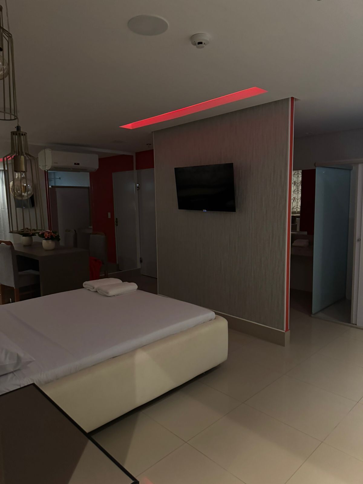 Una habitación de hotel moderna con cama, televisión de pantalla plana, escritorio con silla y armario.