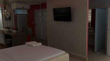 Una habitación de hotel moderna con cama, televisión de pantalla plana, escritorio con silla y armario.