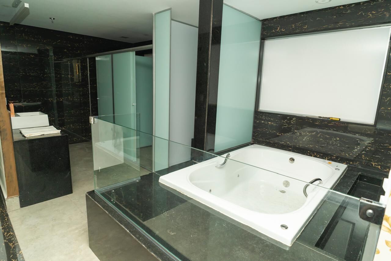 Un baño moderno con una bañera de hidromasaje con mampara de vidrio, paredes de mármol y un recinto de ducha de vidrio.
