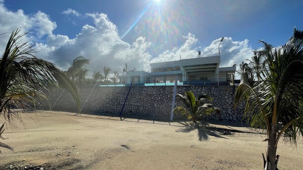A modern building with a stone wall and a pool. - The Noble Retreat, your slice of paradise on Jamaica’s breathtaking North Coast. (Llandovery, St. Ann)