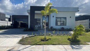 A modern building with a flat roof, large windows, and a well-maintained lawn with a few young trees. - The Noble Retreat, your slice of paradise on Jamaica’s breathtaking North Coast. (Llandovery, St. Ann)