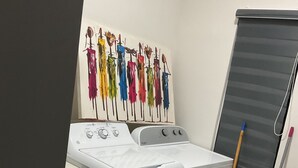A laundry room with a washing machine, a drying rack with colorful clothes, a mop, and a bucket. - The Noble Retreat, your slice of paradise on Jamaica’s breathtaking North Coast. (Llandovery, St. Ann)