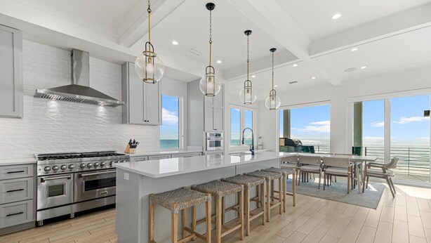 A modern kitchen with a large island, stainless steel appliances, and a view of the ocean. - NEW Rental!!! Viviana 1~Beach Lovin - Private Pool Beach Front Home (Perdido Key)
