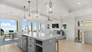 A spacious kitchen with a large island, modern pendant lights, and a view to the outdoors. - NEW Rental!!! Viviana 1~Beach Lovin - Private Pool Beach Front Home (Perdido Key)