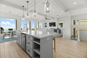 A spacious kitchen with a large island, modern pendant lights, and a view to the outdoors. - NEW Rental!!! Viviana 1~Beach Lovin - Private Pool Beach Front Home (Perdido Key)