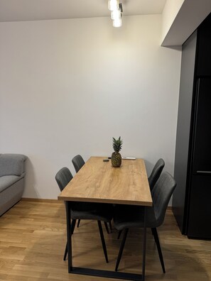 Ein Essbereich mit einem Holztisch, vier Stühlen, einer Ananas als Dekoration und einer modernen Leuchte.