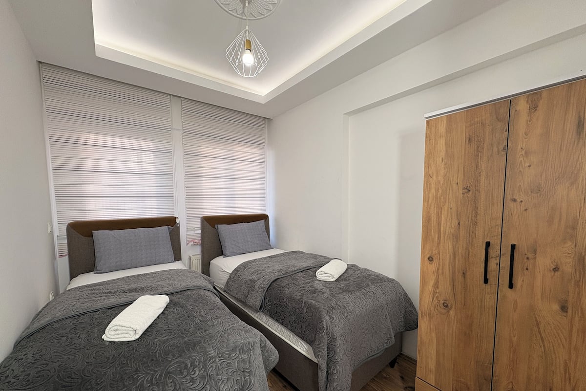 A bedroom with two beds, a wardrobe, and a skylight.