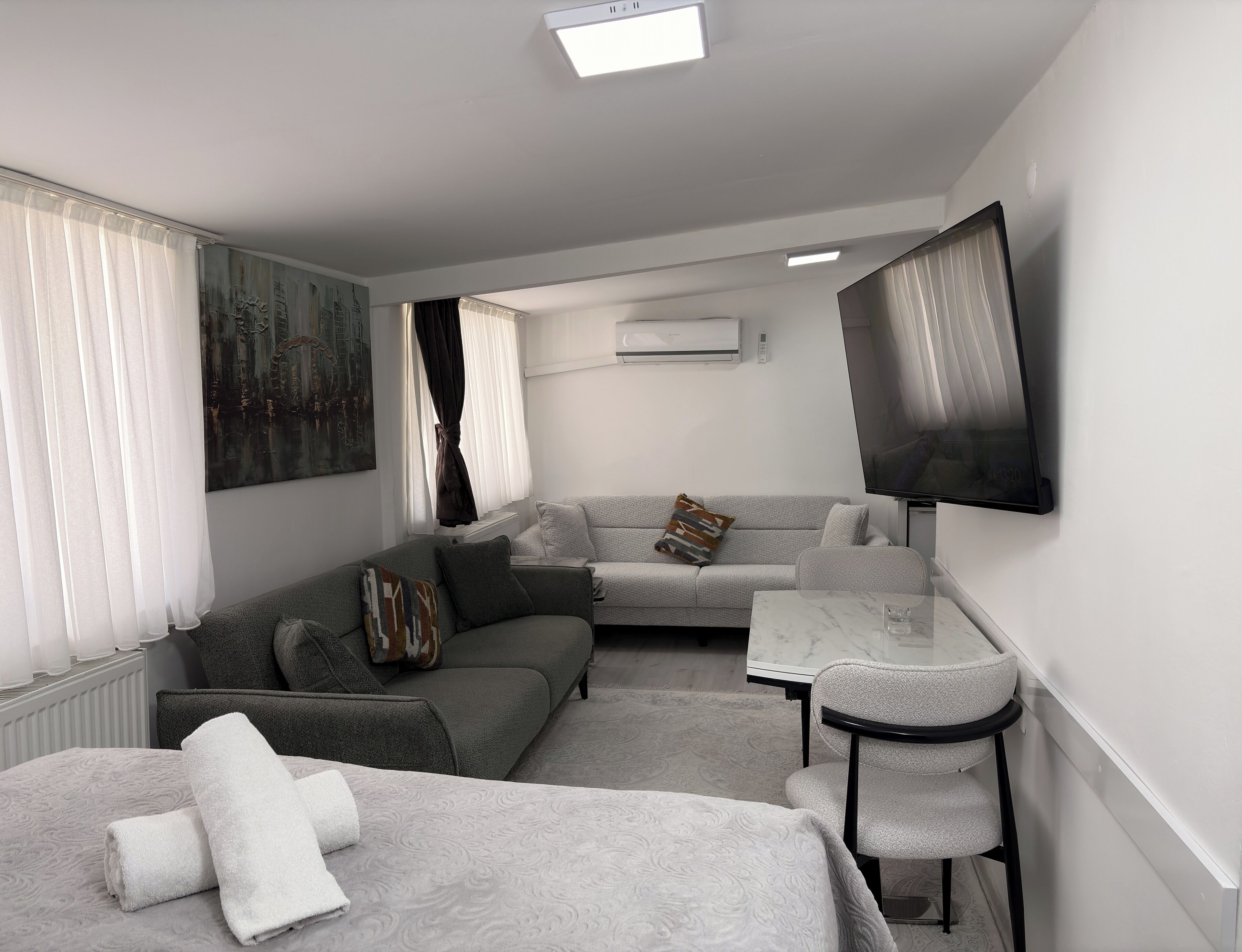 Een moderne hotelkamer met een bank, een tafeltje, een televisie en een bed.