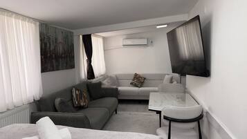 Een moderne hotelkamer met een bank, een tafeltje, een televisie en een bed.