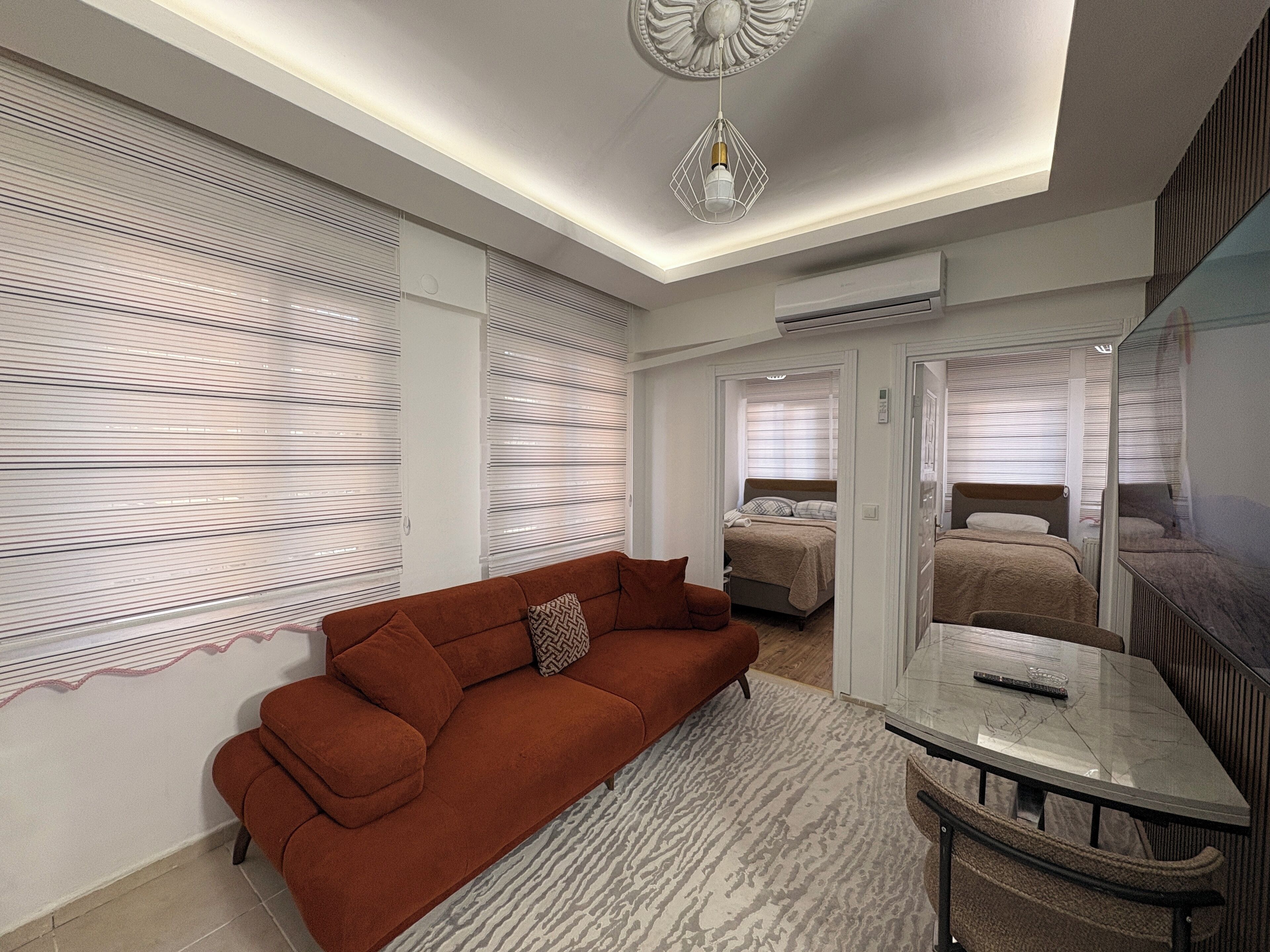 A modern hotel room with a sofa, a small table, a bed, and a mirror.