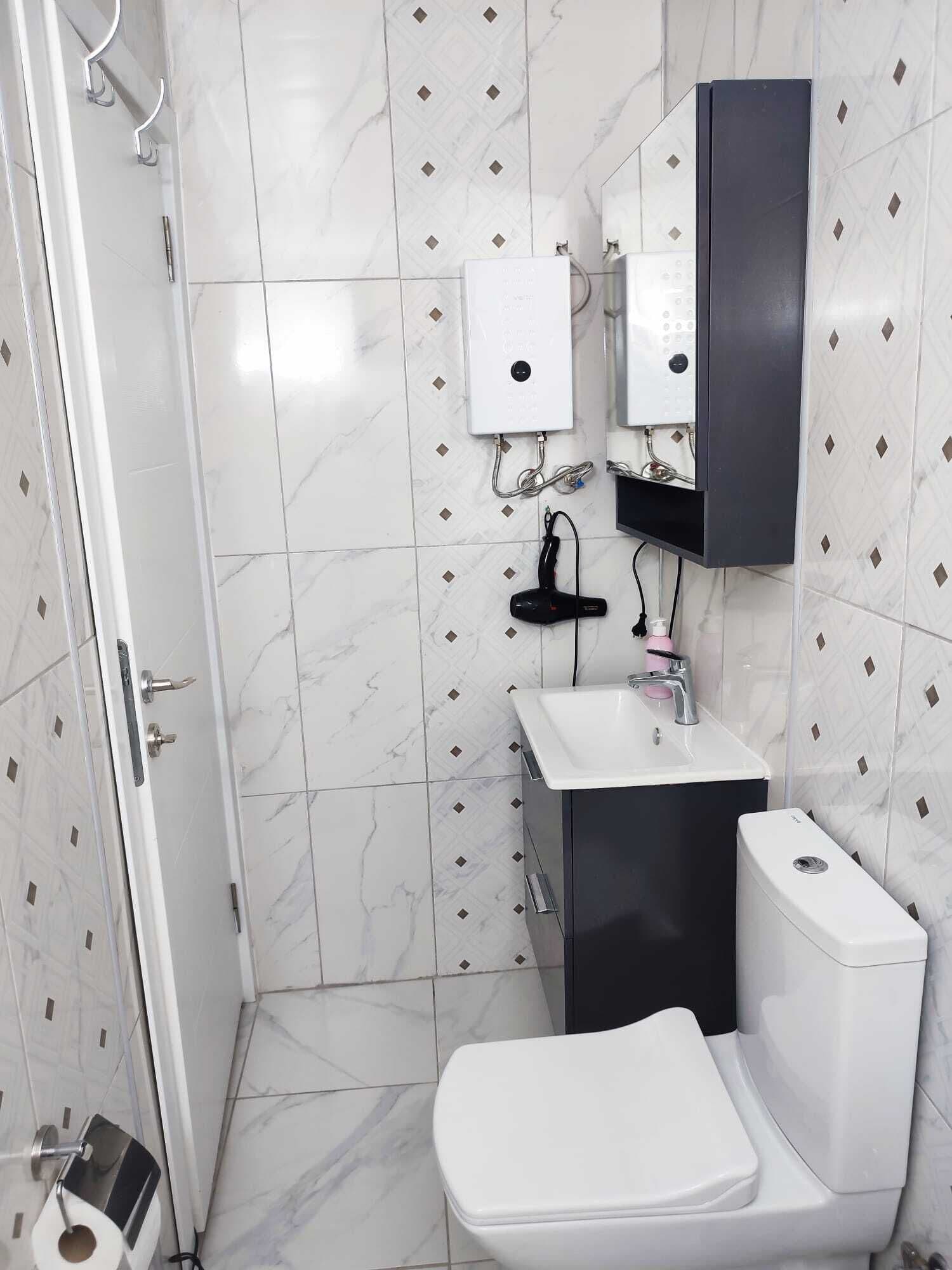 A bathroom with a toilet, sink, and shower.