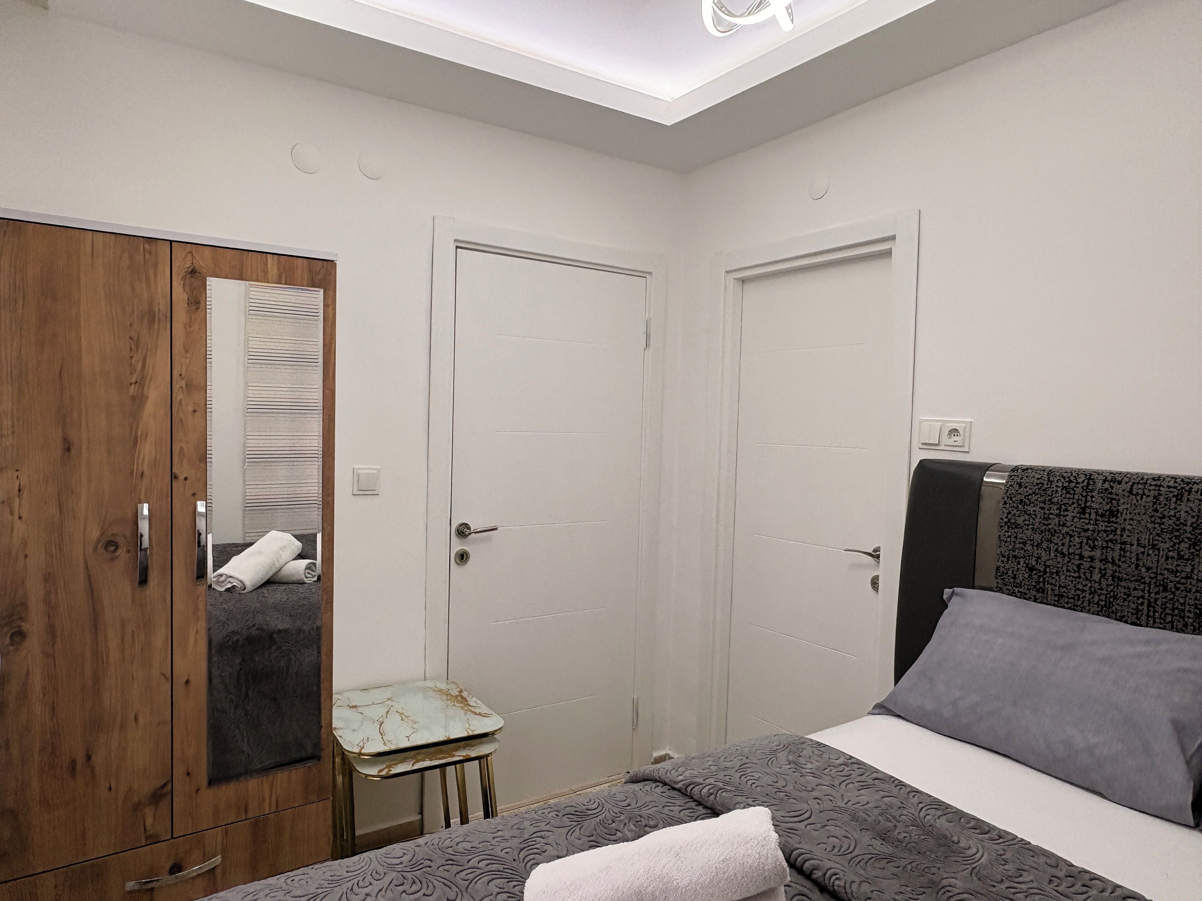 Una camera da letto con un letto, un armadio, un tavolino e una lampada a soffitto.