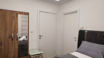 Una camera da letto con un letto, un armadio, un tavolino e una lampada a soffitto.