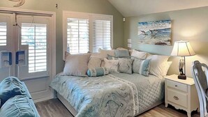 Een slaapkamer met een groot bed, een nachtkastje, een lamp en een schilderij aan de muur.