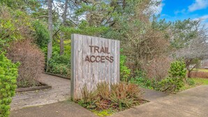 Un letrero de madera que dice "TRAIL ACCESS", rodeado de follaje y árboles.