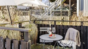 An outdoor seating area with a table, two wine glasses, and a blanket.