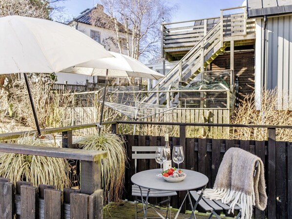 An outdoor seating area with a table, two wine glasses, and a blanket.