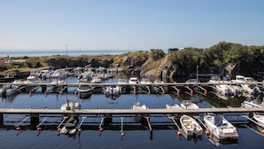 A marina with boats docked at wooden piers, surrounded by rocky terrain and greenery.