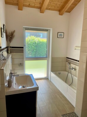 A modern bathroom with a sink, vanity, and bathtub. - Cozy and quiet vacation apartment with a terrace and garden (Seebruck)