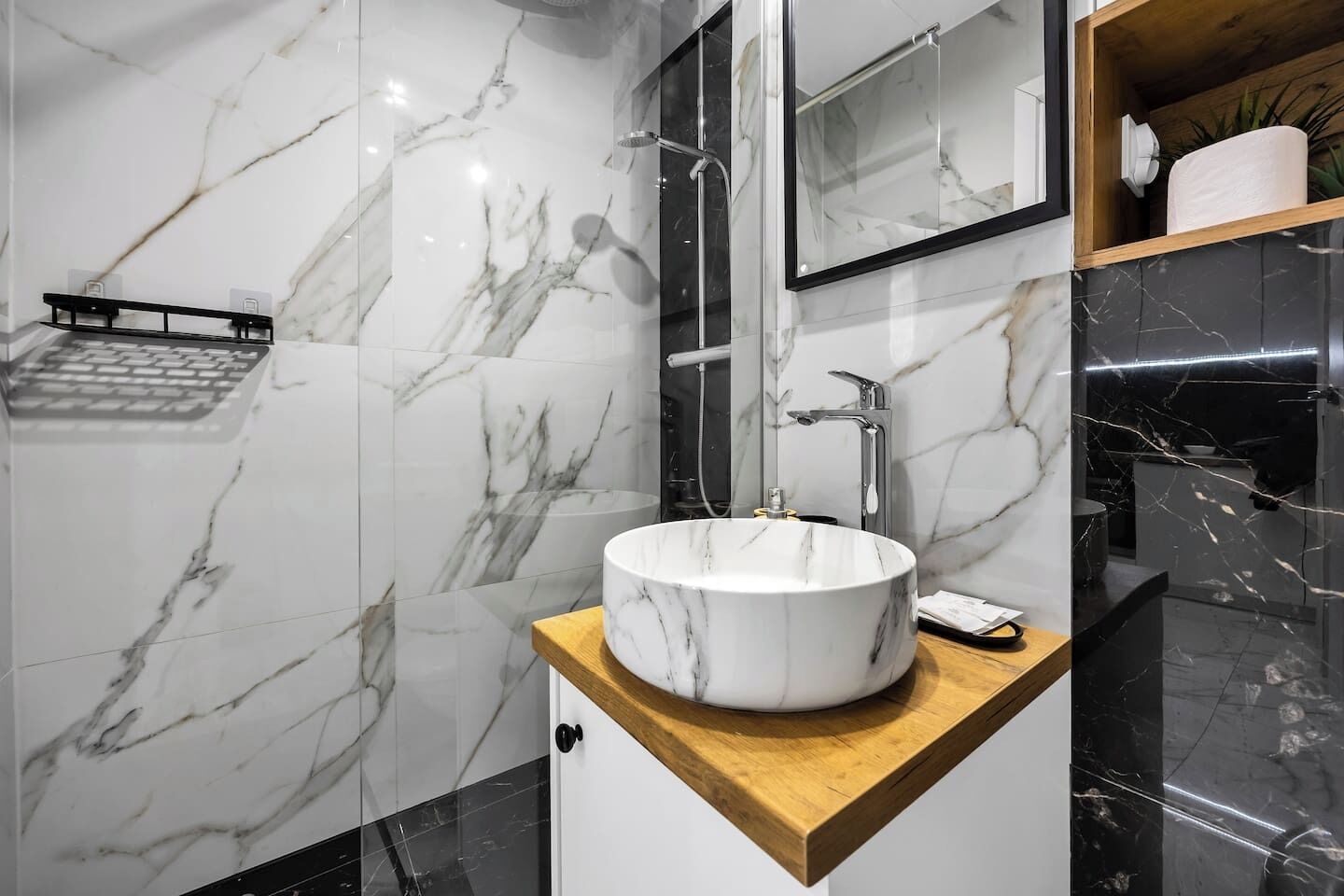 A modern bathroom with a marble vanity, a round sink, and a mirror above the sink.