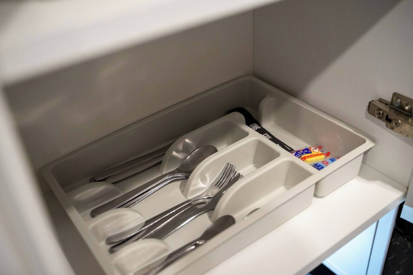 A drawer with utensils and condiments.