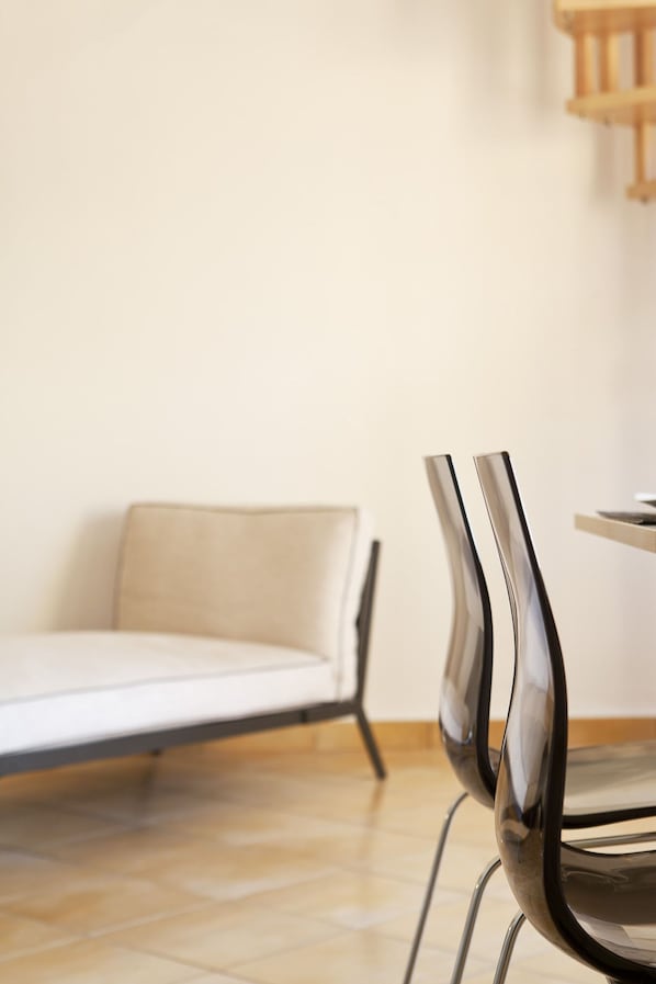 A minimalist room with a sofa and a chair. - Thireas Hotel (Santorini)