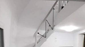 A staircase with white railings and a small table beside it. - Leta Santorini (Santorini)