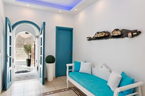 Ein modernes Interieur mit einem weißen Sofa, Türkis-Kissen, einer blauen Tür und einer Wanddekoration.
