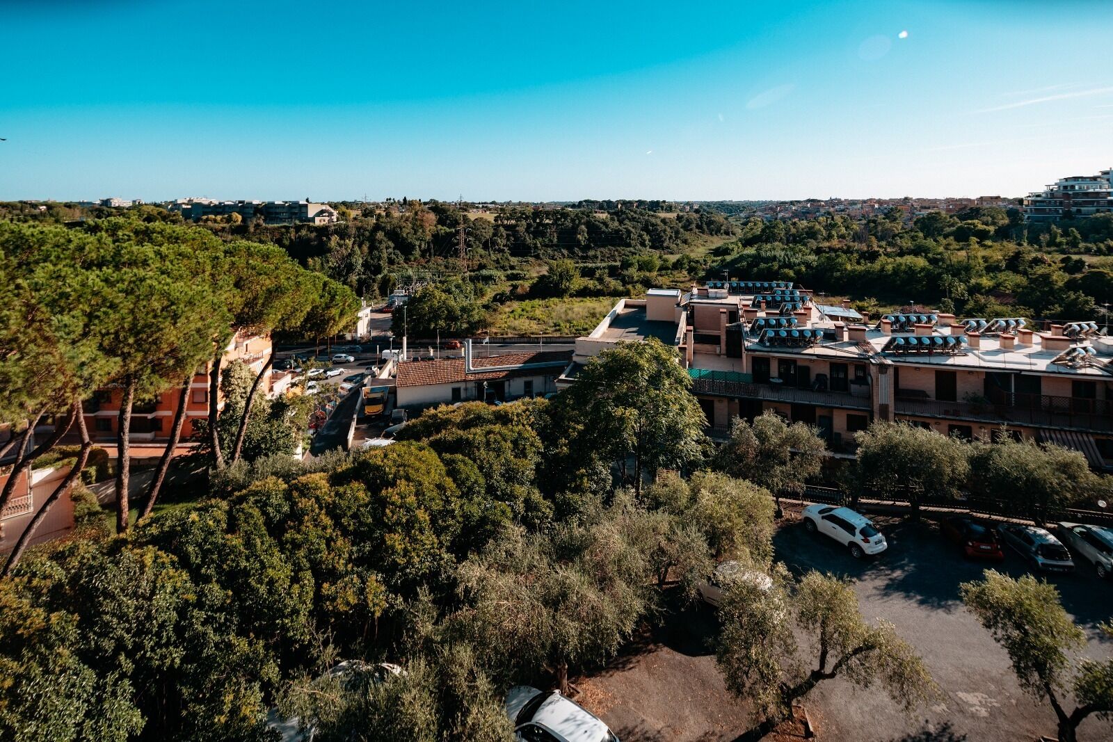 An aerial view of a residential area with multiple buildings, including a large complex with solar panels on the roof.