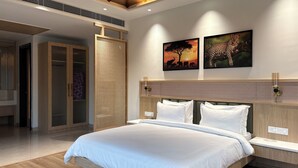 A modern bedroom with a large bed, wooden headboard, and two wall-mounted nightstands. - Corbett Anandavana (Ramnagar)