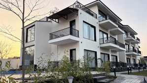 A multi-story residential building with balconies, a tiled walkway, and surrounding vegetation. - Corbett Anandavana (Ramnagar)