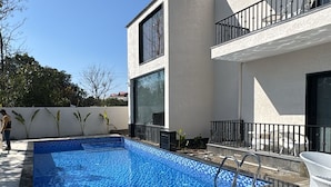 A rectangular swimming pool with blue mosaic tiles, surrounded by a white wall and a balcony with black railings. - Corbett Anandavana (Ramnagar)