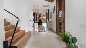 A modern interior with a wooden staircase, a zebra-patterned rug, and a potted plant. - Architectural Gem w/ Rooftop Terrace + Heated Pool (Austin)
